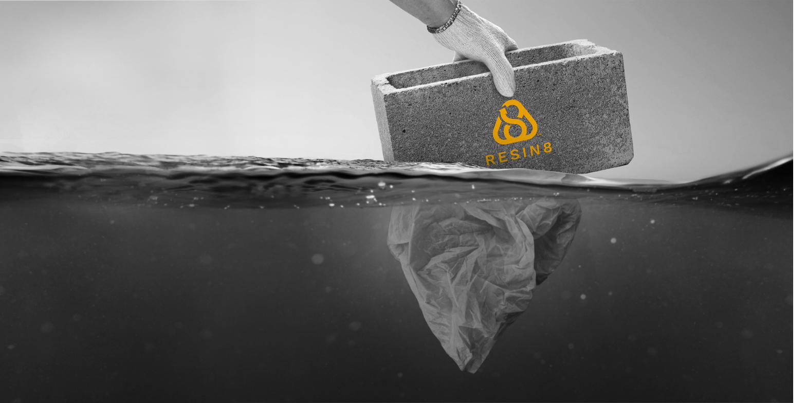 A RESIN8 concrete block lifted from the sea above a sinking plastic bag